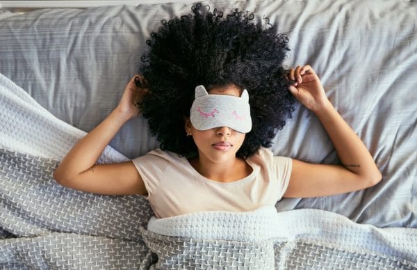 Young woman sleeping with a mask on in bed