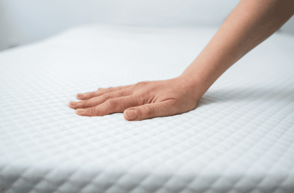 Hand pressing on a new mattress